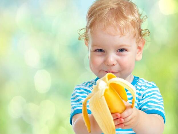 Un niño comiendo un plátano./adobe stock