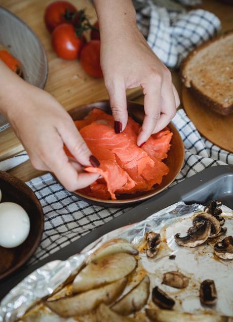 Mujer cocinando con salmón/PEXELS