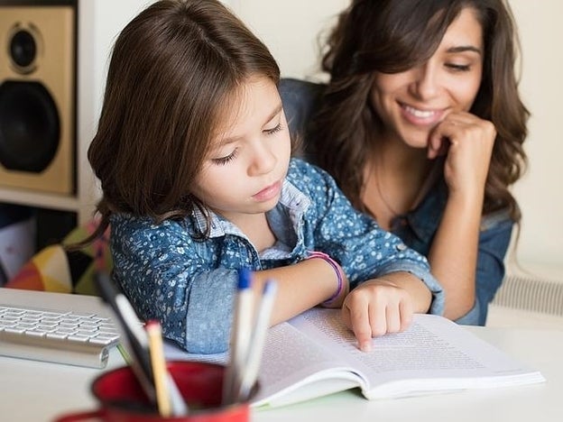 Madre enseñando a leer a su hija/Fotolia