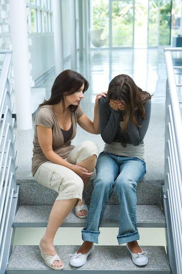 Una mujer intenta consolar a otra en las escaleras de la oficina./GTRES