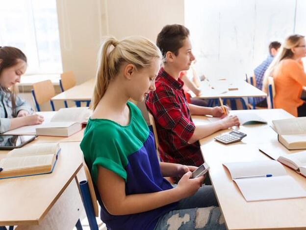 Alumna con el móvil durante una clase/fotolia