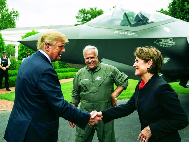 En los jardines de la Casa Blanca, el año pasado, Marillyn Hewson saluda al presidente Donald Trump ante Alan B. Norman, director jefe de pilotos de pruebas del F-35, un avión de combate con capacidad furtiva./getty