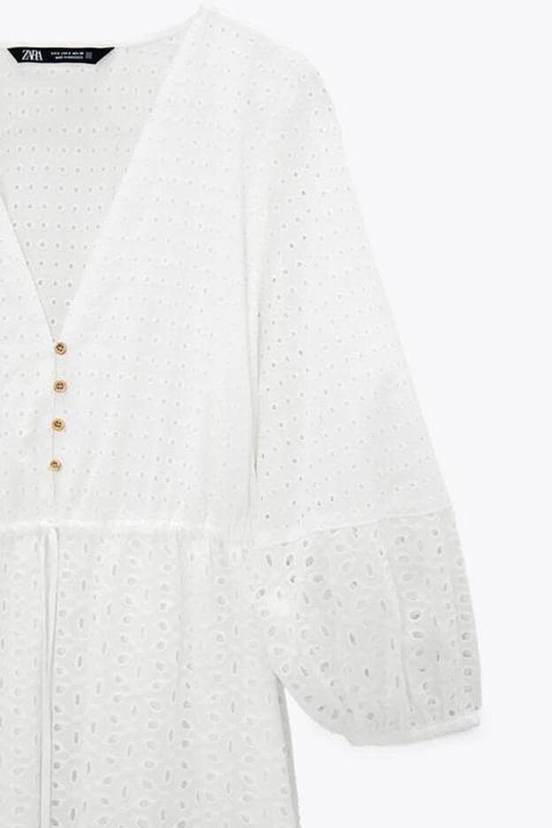 En color blanco, este vestido con escote de pico cuenta con botones en la parte central y un volante en el bajo.