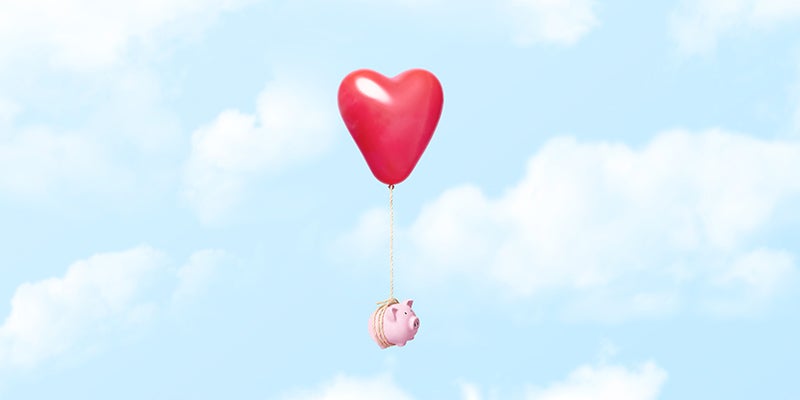 Horizontal conceptual image of a single pink piggy bank tied to a red heart balloon with a rope floating through the clouds, could illustrate concepts like couple and relationship finances, dating costs, moving away from home, or even opposite things like loosing ones savings in a divorce or breakup/