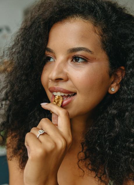 Mujer comiendo nueces/PEXELS