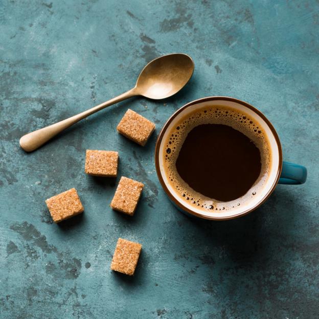 Una taza de café con terrones de azúcar moreno. 