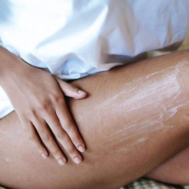 Mujer extendiedo crema para piel atópica sobre las piernas