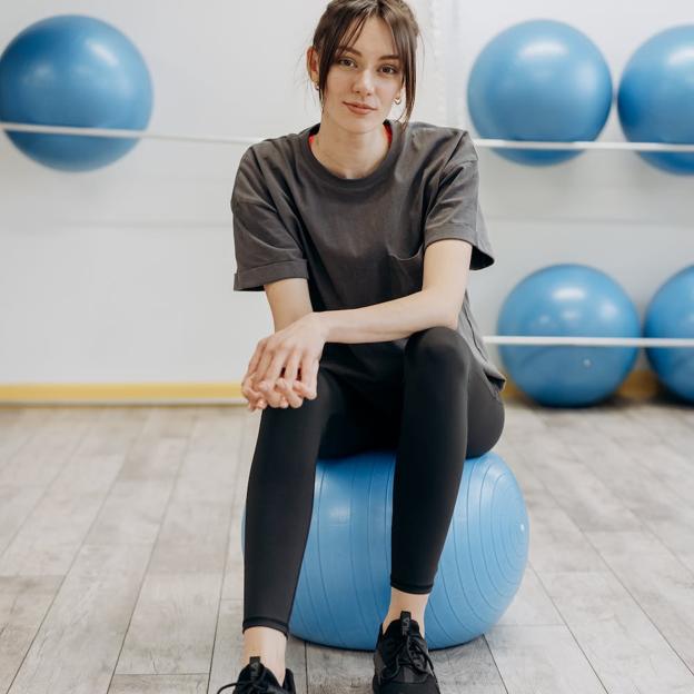 Mujer realizando entrenamiento con pelota bosu. /