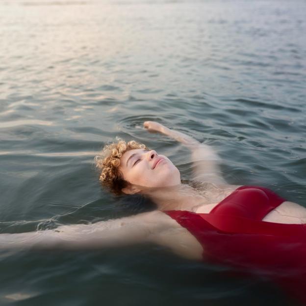 Mujer con bañador rojo nadando en agua fría. 