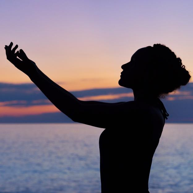 Mujer meditando al anochecer. 