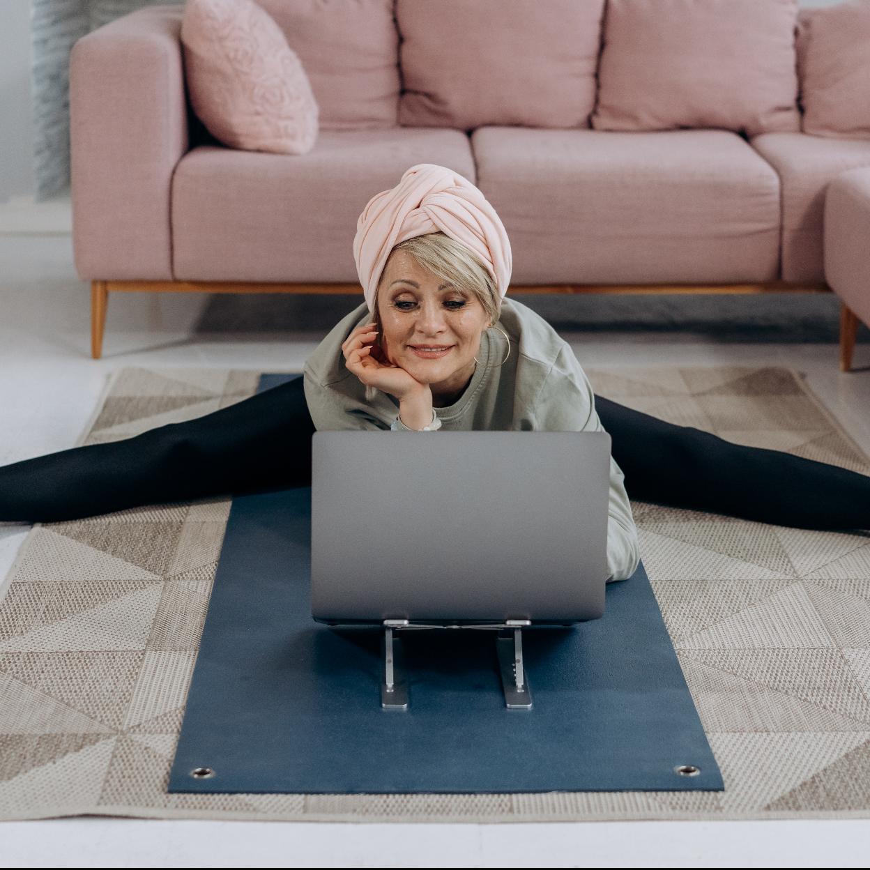 Mujer realizando ejercicios de estiramiento ante el ordenador. /pexels