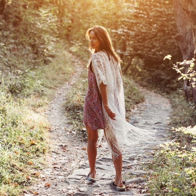 Mujer andando por un camino en mitad del campo. 