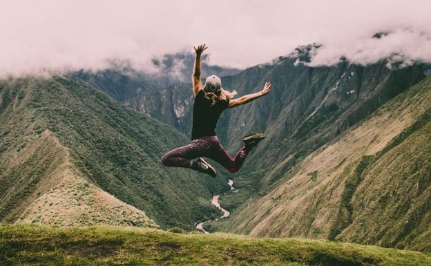 Mujer dando un salto tras una larga caminata. /