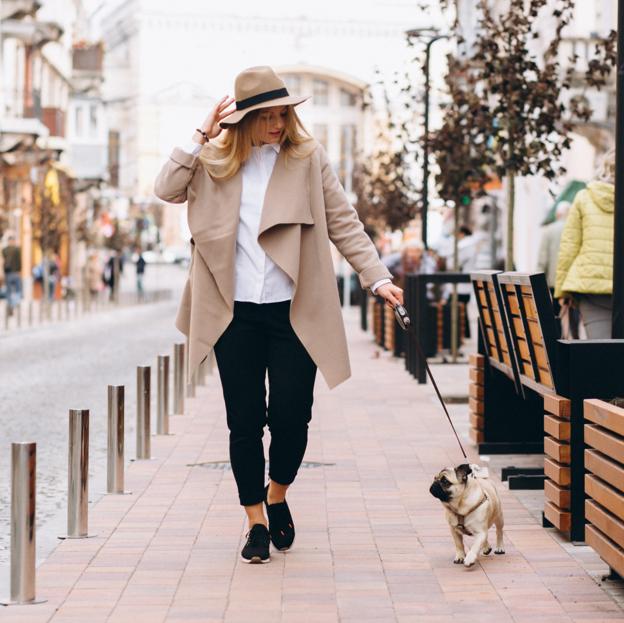 Mujer paseando por la ciudad junto a su perro. 