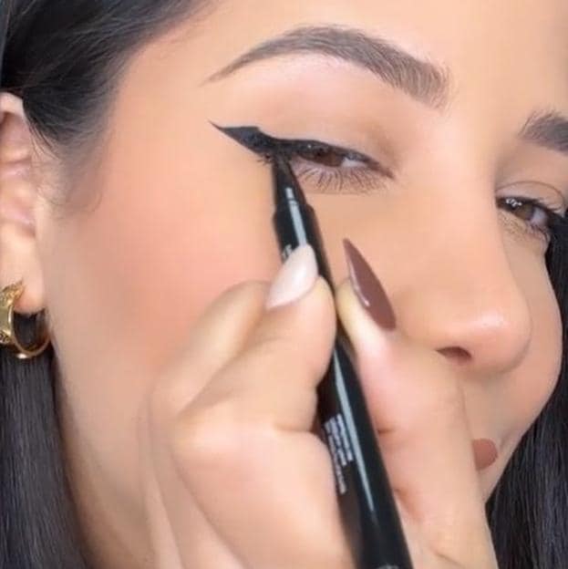 Influencer haciendo eyeliner de punta de flecha para párpado caído