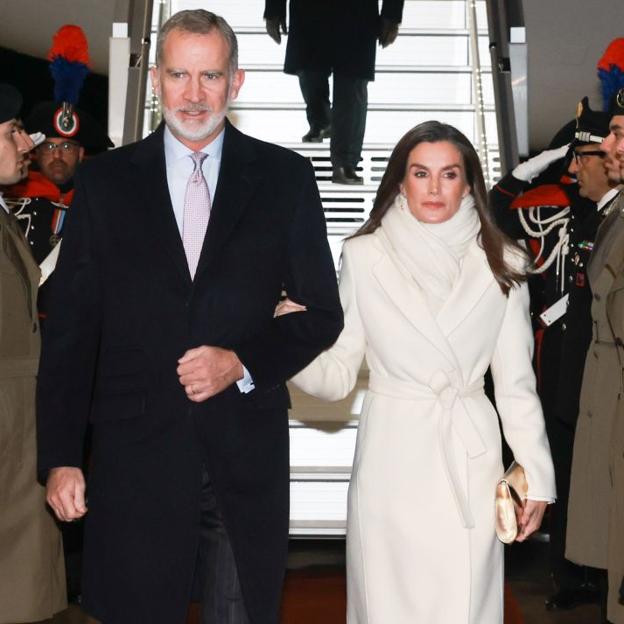 La reina Letizia sorprende en su llegada a Italia con un impoluto look blanco: abrigo largo y zapatos metalizados