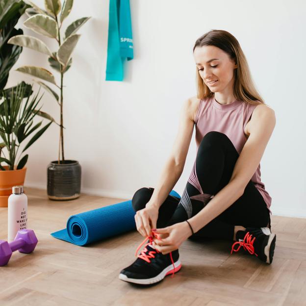 Mujer preparándose para hacer yoga sobre esterilla. 